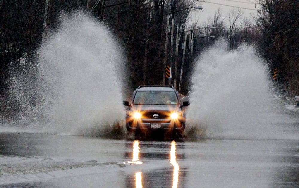 A vehicle blasts its way through a flooded Stony Road, in Lancaster, N.Y. Western New York has localized flooding from melting snow following last week's lake-effect snow.