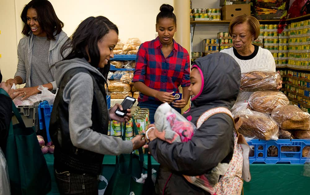 From left, First lady Michelle Obama, Sasha Obama, and the first lady's mother Marian Robinson, distribute food at 