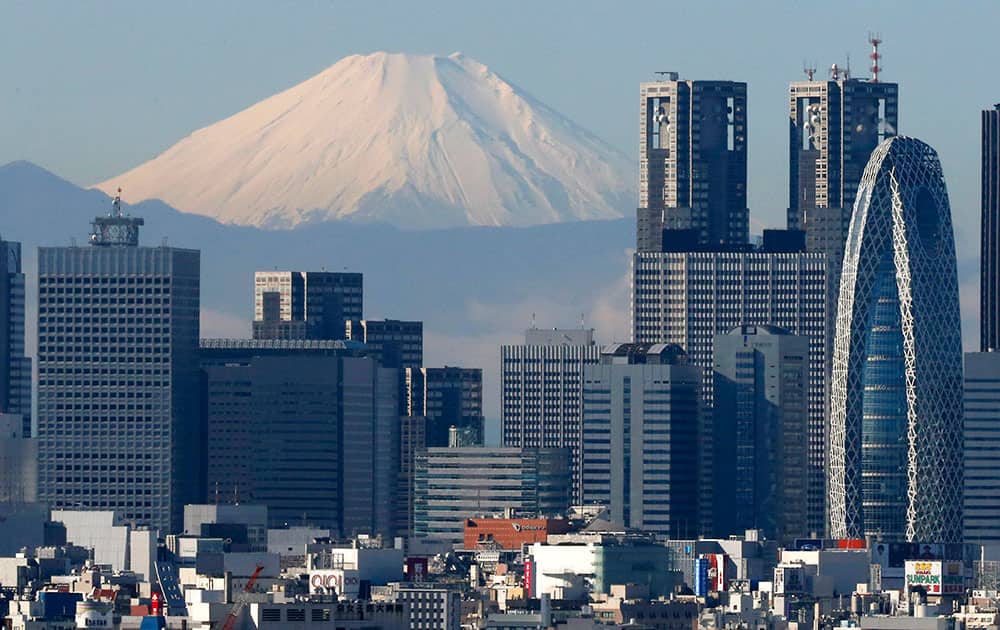 Snow-covered 3,776-meter (12,388-foot) Mount Fuji is seen behind Tokyo's skyscrapers, Japan.