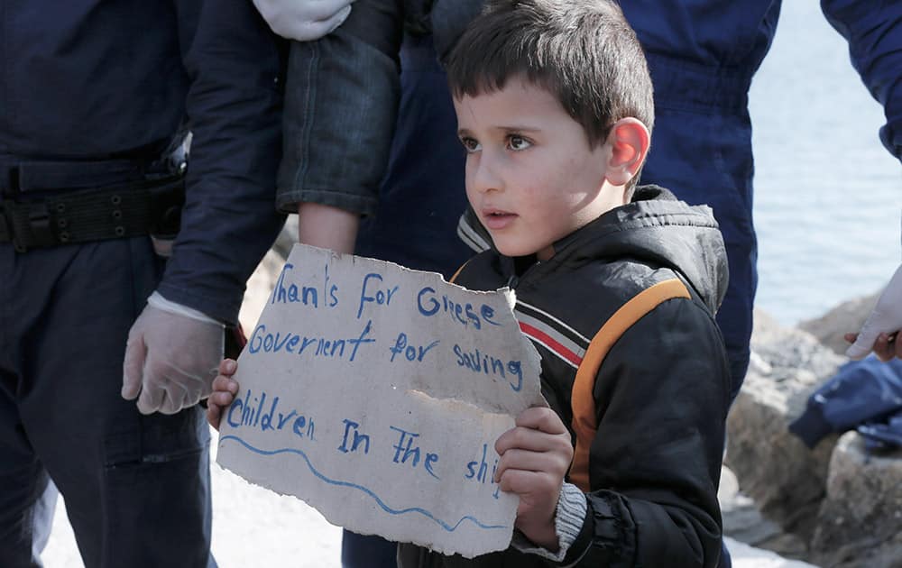 A young boy holds a paper just after disembarking from a crippled freighter carrying hundreds of refugees trying to migrate to Europe, at the coastal Cretan port of Ierapetra, Greece.