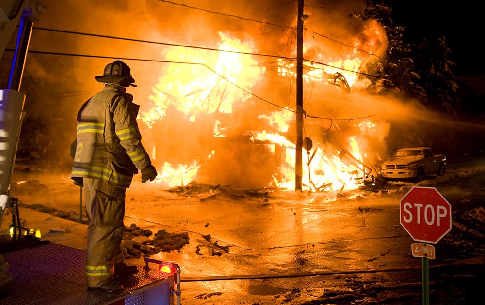 A firefighter looks on as a fire rages on W. Saylor St., in Atlas, Pa. A vacant building was destroyed in the blaze which is considered suspicious.