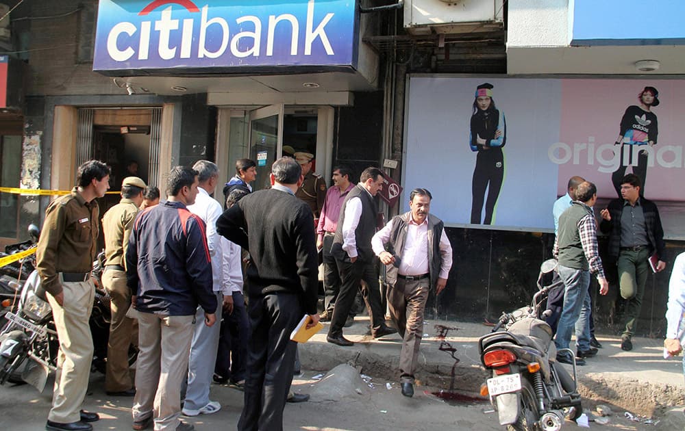 Police and officials investigate near a Citibank, where two men on a motorcyle shot at a security guard looted Rs 1.5 Cr from cash van in Kamla Nagar area in New Delhi.