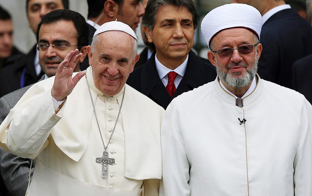 Pope Francis waves to journalists as he stands by Istanbul Mufti Rahmi Yaran upon their arrival to the Blue Mosque in Istanbul, Turkey.