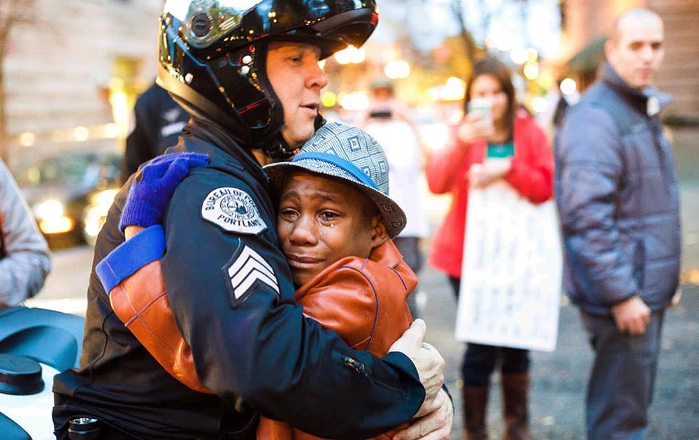 Portland police Sgt. Bret Barnum, left, and Devonte Hart, 12, hug at a rally in Portland, Ore., where people had gathered in support of the protests in Ferguson, Mo.