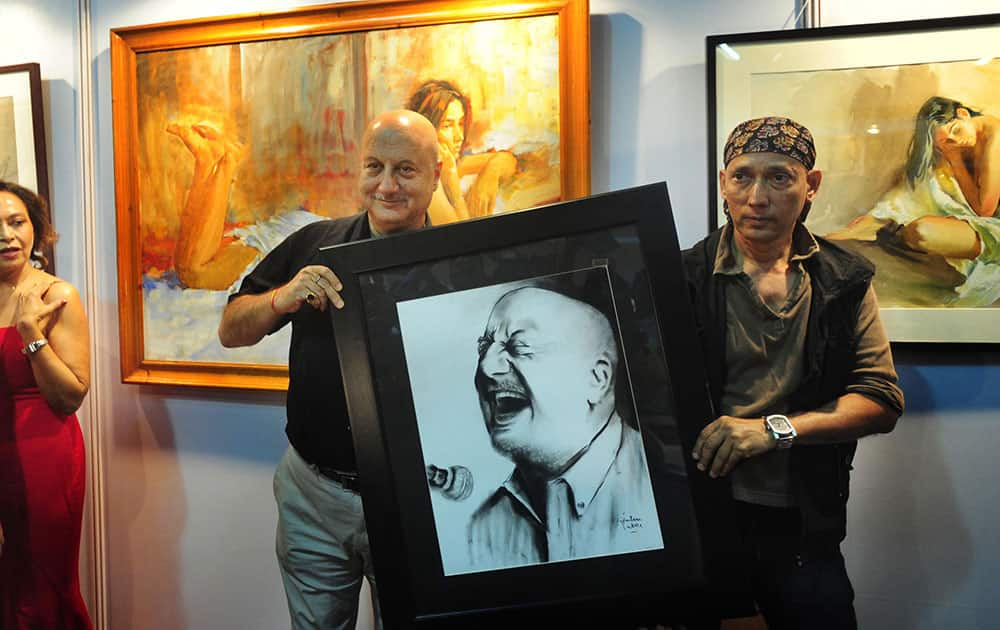 Actor Anupam Kher with his charcoal painting by artist Gautam Patole after the launch of seen and unseen paintings of the late artist John Fernandes’s coffee table book by his wife Agnela (left) during the India Art Festival at Nehru centre at Worli. -dna