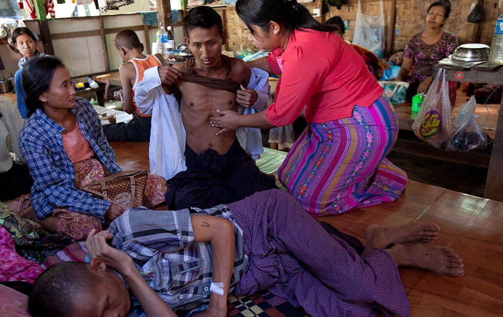 Phyu Phyu Thin, right, a parliament member of Myanmar Opposition Leader Aung San Suu Kyi's National League for Democracy party, examines an HIV patient while other patients rest at her HIV/AIDS Care Center in the outskirts of Yangon, Myanmar.