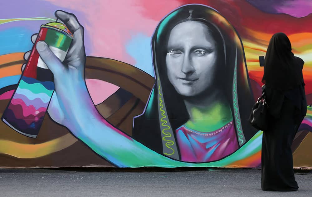 An Emirati woman takes a photo in front of government-sanctioned graffiti entitled 