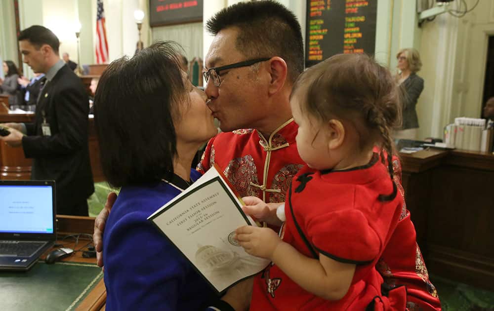 Freshman Assemblyman Kansen Chu, D-Fremont, receives a kiss from his wife, Daisy, as he holds their granddaughter Kimberly Blomquist, 21 months, after taking the oath of office at the Capitol in Sacramento, Calif.