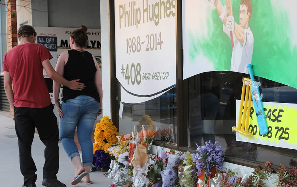 A couple leave after laying a floral tribute at a shopfront of the hometown of Australian cricket player Phillip Hughes in Macksville, Australia.