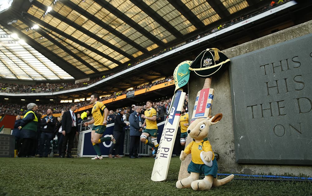 Members of the Australian rugby union team take to the pitch with cricket bats, Australian caps and a mascot are placed on the side of the pitch as a mark of respect to Australian cricketer Phil Hughes who died earlier this week, after being hit by a ball in a match at the Sydney Cricket Ground, prior to the international rugby union match between England and Australia at Twickenham stadium in London.