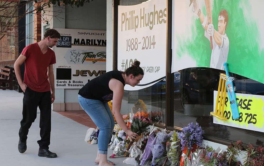 A woman lays flowers to pay tribute to the late Australian cricket player Phil Hughes outside a shop in Macksville, Australia.