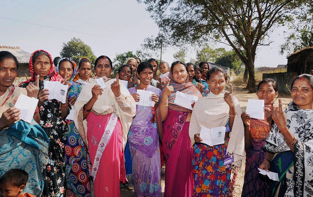 Voters show their ID cards and inked fingers after casting their votes for assembly elections outside a polling station at Karra, Khunti near Ranchi.