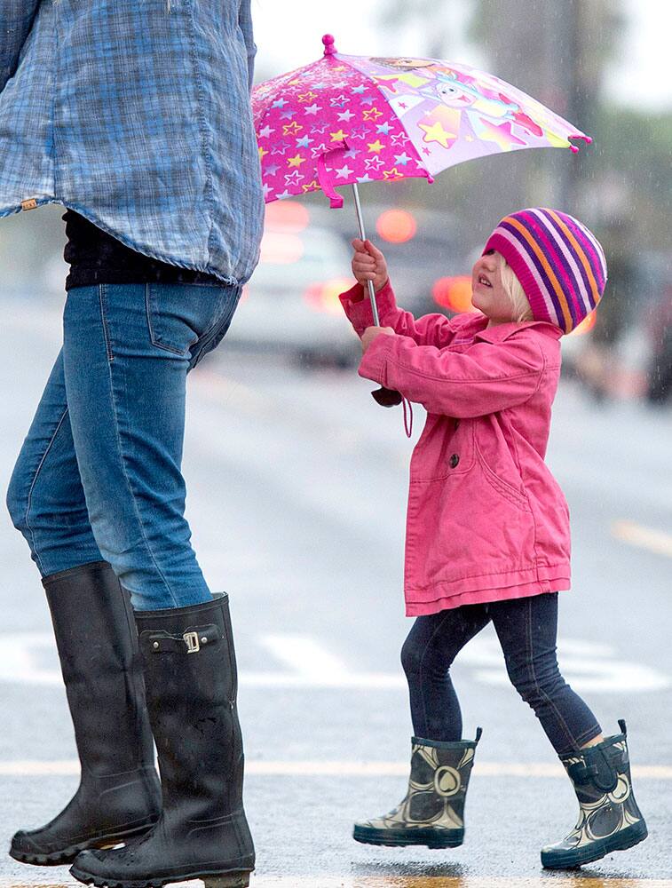 Shea Reilly is dressed for the weather in Seal Beach, Calif., Tuesday, Dec. 2, 2014, as a powerful Pacific storm swept through California.