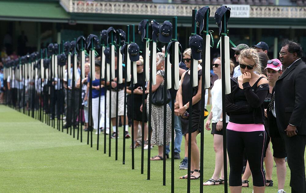 Mourners gather for a memorial service at the Sydney Cricket Ground and look at 63 bats with inscriptions detailing the career of cricketer Phillip Hughes in Sydney.