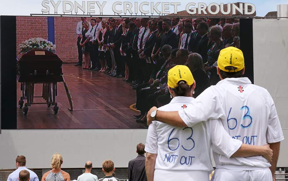 A couple embraces as mourners gather at the Sydney Cricket Ground to watch the funeral for cricketer Phillip Hughes in Sydney.