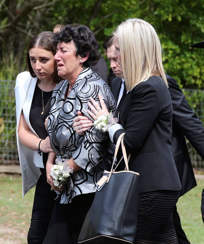 Virginia Hughes, center, mother of Australian cricketer Phillip Hughes, is supported by mourners as they walk behind her son's coffin during his funeral in Macksville, Australia.