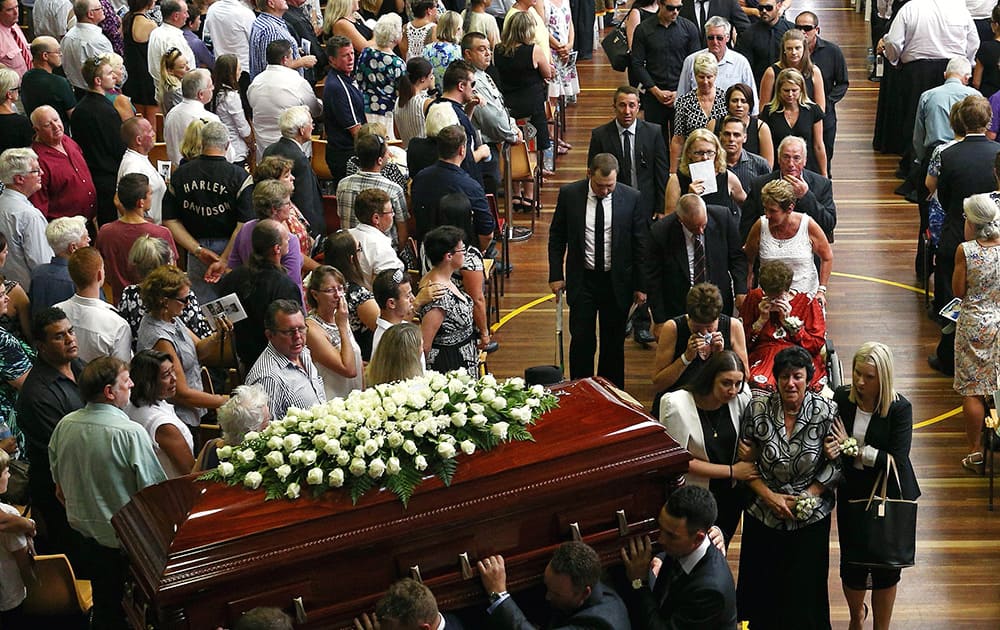 The coffin of Phillip Hughes is carried down the aisle as his mother, Virginia Hughes, is comforted during his funeral in Macksville, Australia.