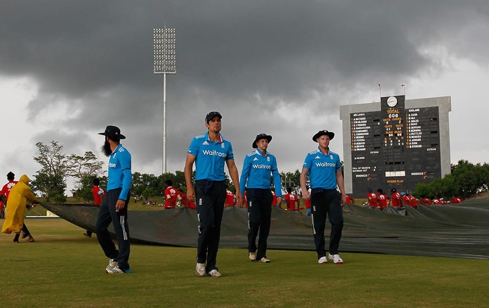 England's cricket team members walk off the field after play was stop due to bad light, as rain clouds hover over the stadium during the third one day international cricket match between Sri Lanka and England in Hambantota, Sri Lanka.