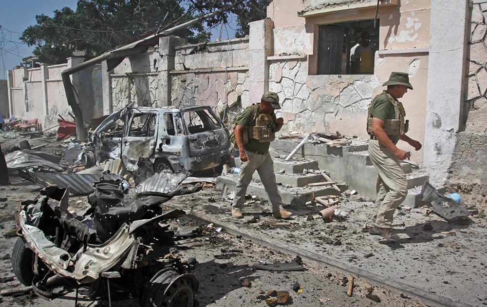 Foreign security officers inspect wreckage at the scene of a suicide car bomb attack that targeted a United Nations convoy, outside the airport in Mogadishu, Somalia.