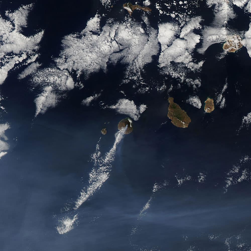 This photo made available by NASA shows a plume of smoke trailing from the Pico do Fogo volcano, center, in the Cape Verde islands off West Africa. 