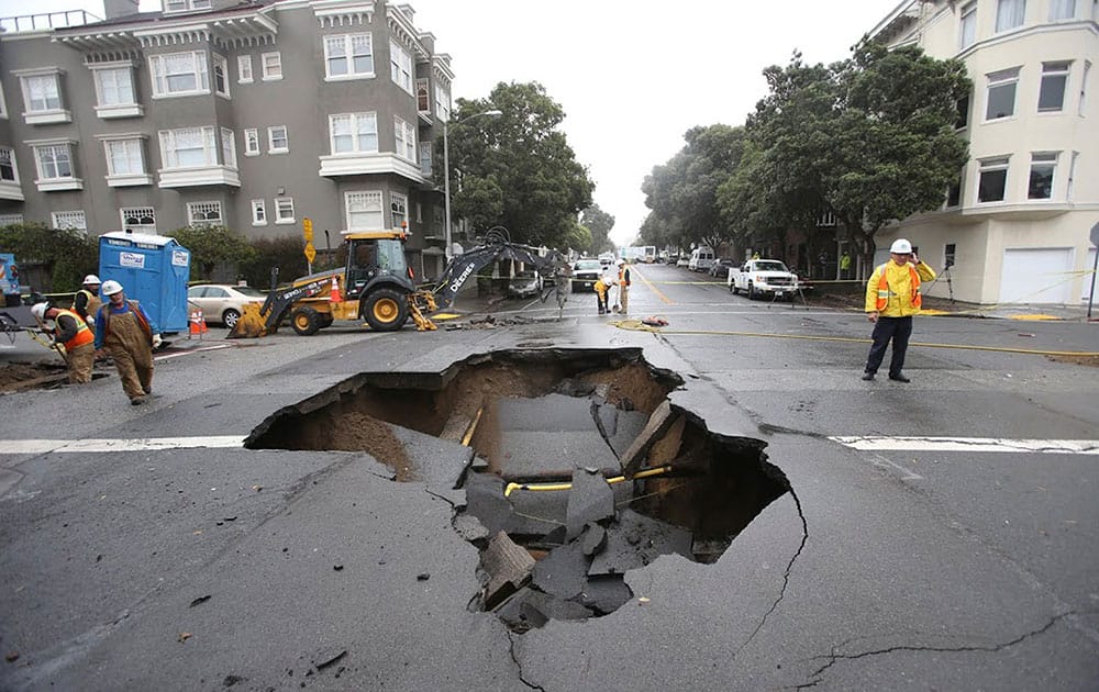 Crews work around a sinkhole that formed in the Richmond district after a night of heavy rains, in San Francisco.