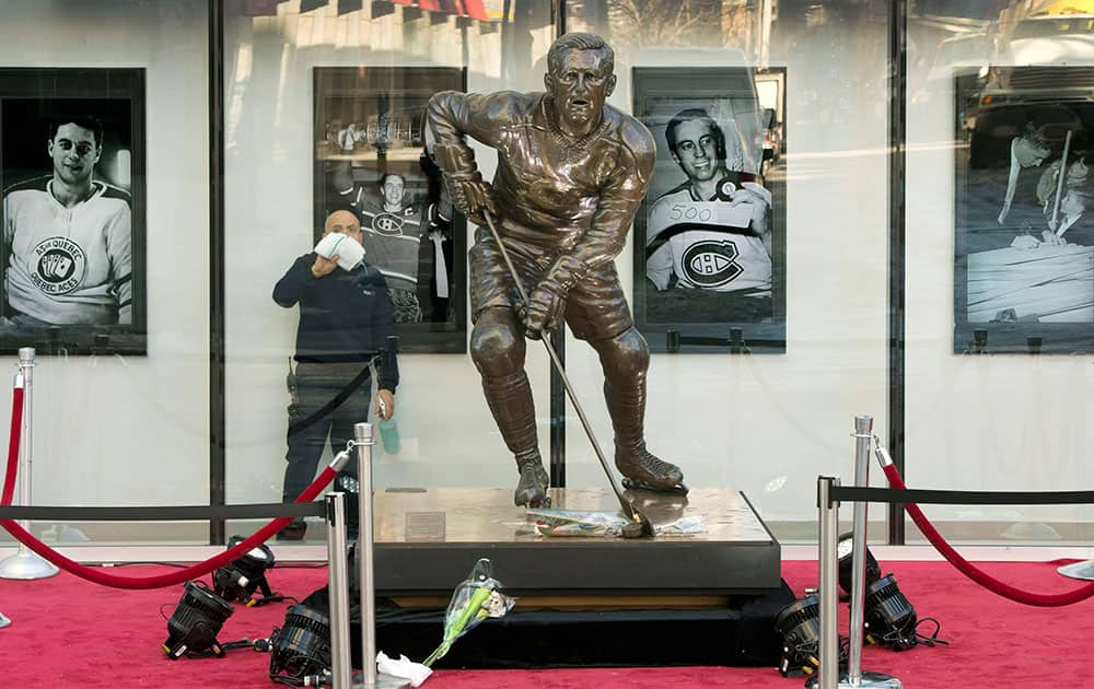 A worker cleans the windows around a memorial for hockey Hall of Famer Jean Beliveau in front of the Bell Center, in Montreal.