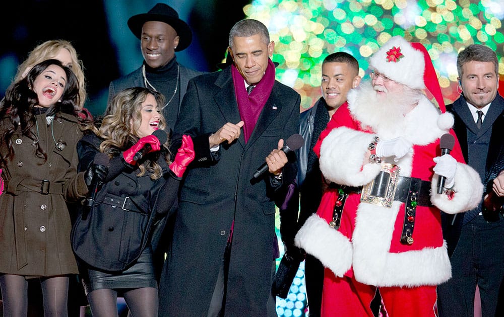 President Barack Obama dances on stage with Santa, members of Fifth Harmony, Nico & Vinz and The Tenors, behind, during the National Christmas Tree lighting ceremony at the Ellipse near the White House in Washington.