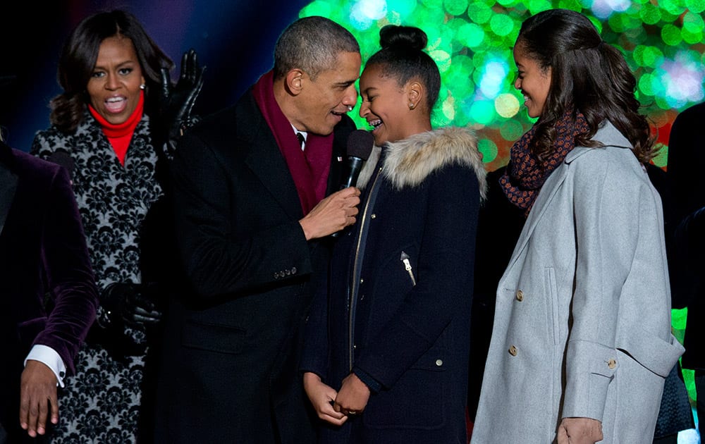 Michelle Obama, President Barack Obama and their daughters, Sasha and Malia, sing on stage during the National Christmas Tree lighting ceremony at the Ellipse near the White House in Washington.