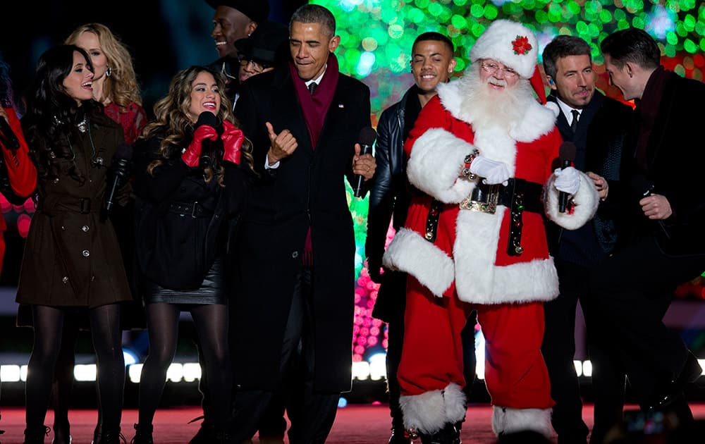 President Barack Obama dances on stage with Santa, members of Fifth Harmony, left, Nico & Vinz and The Tenors, background, during the National Christmas Tree lighting ceremony at the Ellipse near the White House in Washington.