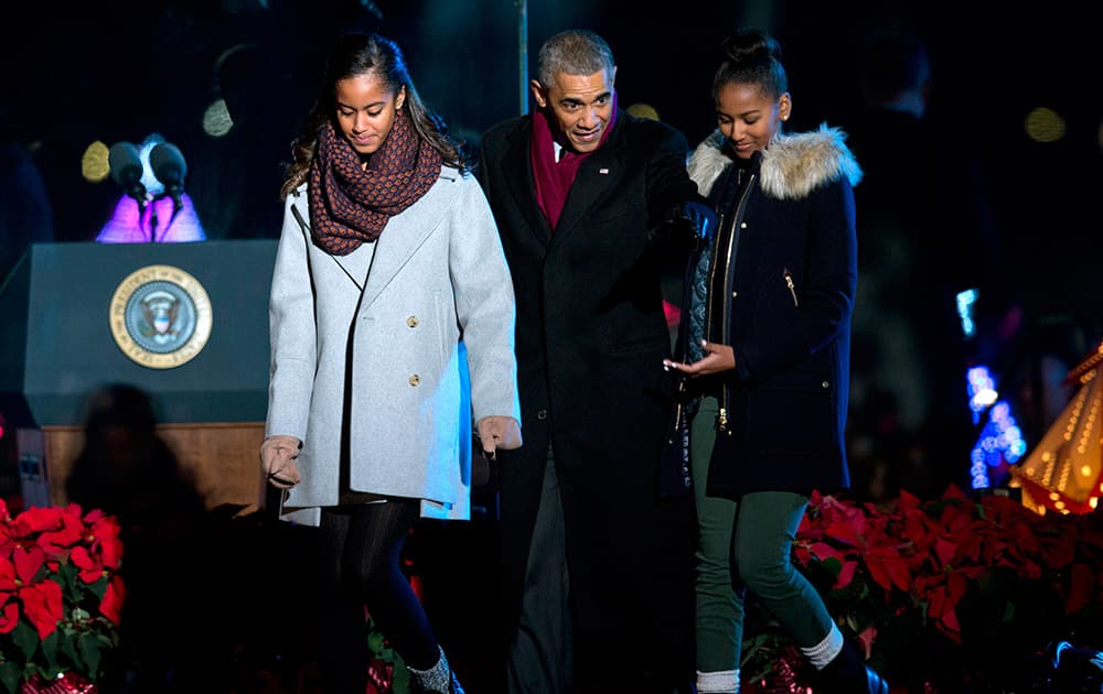 President Barack Obama walks from the stage with his daughters, Malia, left, and Sasha, right, after lighting the 2014 National Christmas Tree during the National Christmas Tree lighting ceremony at the Ellipse near the White House in Washington.