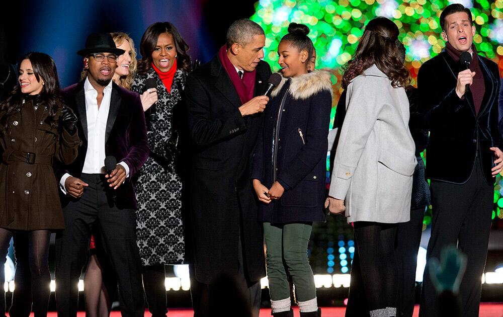 President Barack Obama holds the microphone for his daughter Sasha Obama as they sing on stage during the National Christmas Tree lighting ceremony at the Ellipse near the White House in Washington.