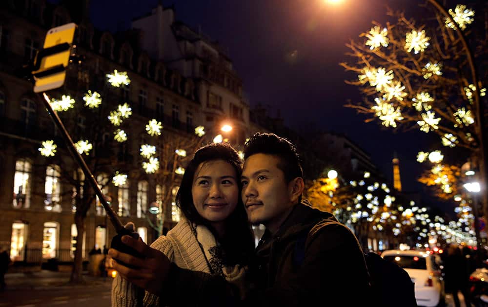 Visitors take selfies next to illuminated decorations on the Champs Elysees, in Paris.