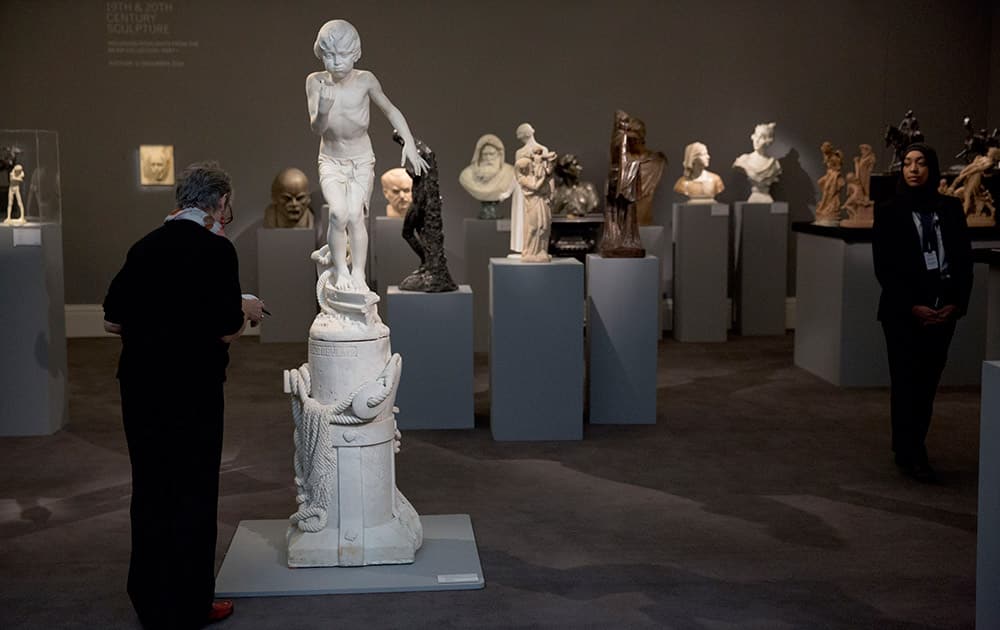 A Sotheby's auction house worker looks at the white marble piece by Spanish sculptor Mariano Benlliure y Gil entitled 'Buzo de Playa', The Diver, beside a selection of works that feature in their forthcoming sale of 19th and 20th century sculpture at their premises in London.