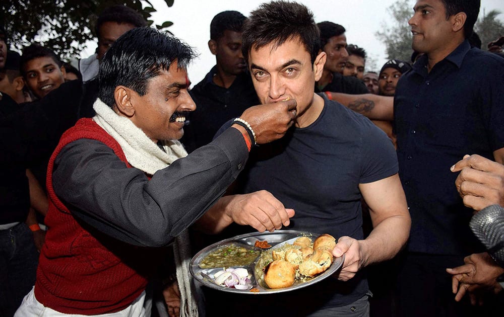 A fan offers Bihars famous food litti chokha to Bollywood star Aamir Khan during the promotion of his upcoming film PK in Patna.