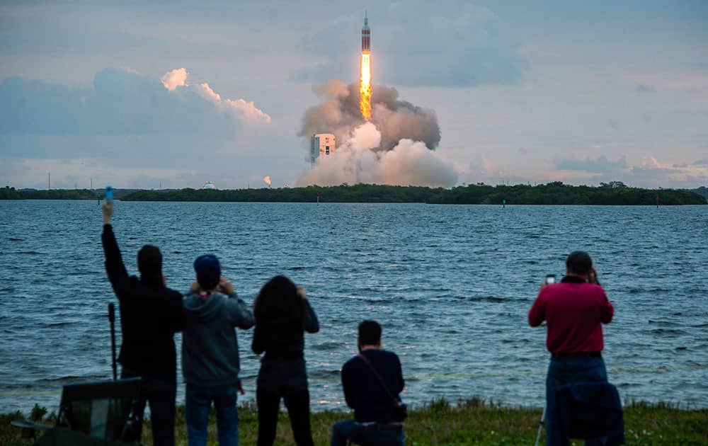 Spectators cheer as the United Launch Alliance Delta 4-Heavy rocket, with NASA’s Orion spacecraft mounted atop, lifts off from the Cape Canaveral Air Force Station, in Cape Canaveral, Fla.