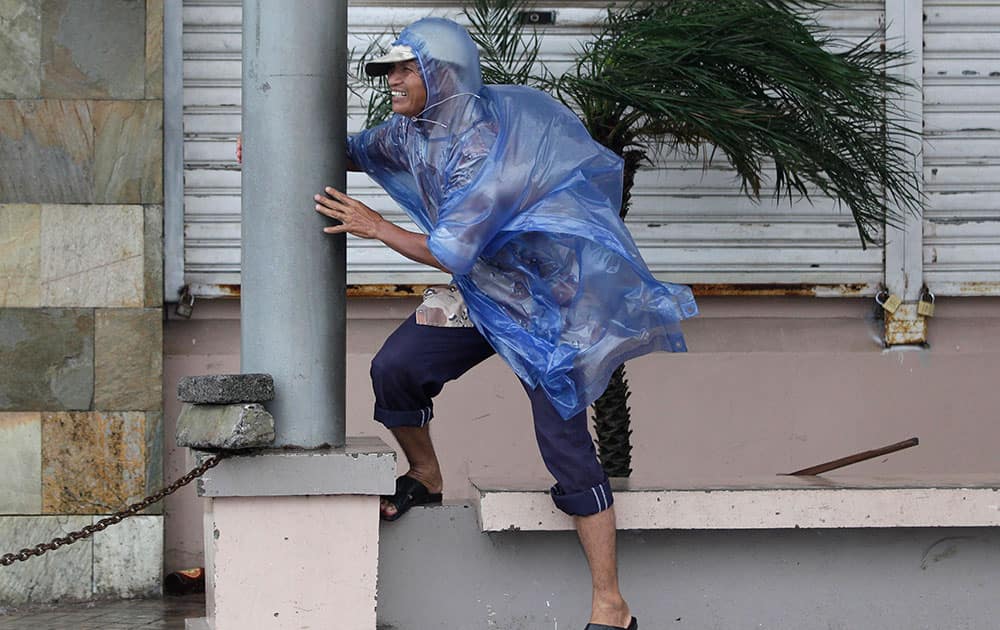 A man holds on to a pole as strong winds blow brought by Typhoon Hagupit in Legazpi, Albay province, eastern Philippines.