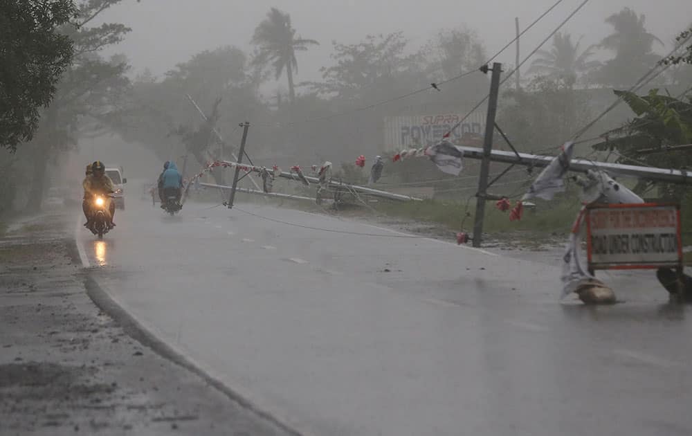 Motorist pass by fallen electrical posts due to strong winds brought by Typhoon Hagupit in Camalig, Albay province, eastern Philippines.