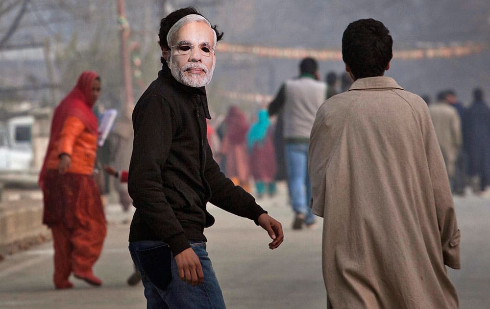 A Kashmiri boy wearing a mask of India's prime minister Narendra Modi walks towards the Sheri Kashmir cricket stadium to attend a campaign rally by Modi ahead of the local elections in Srinagar, India.
