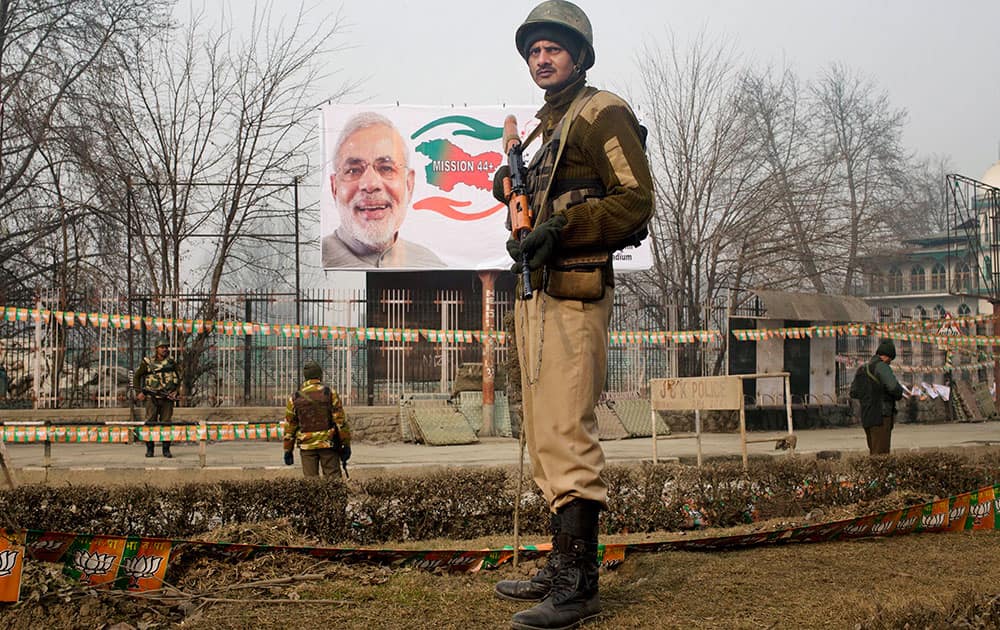 Indian paramilitary soldiers stand guard near Sheri Kashmir cricket stadium where Prime Minister Narendra Modi, portrait seen in the backdrop, is expected to address a campaign rally ahead of local elections in Srinagar, India.