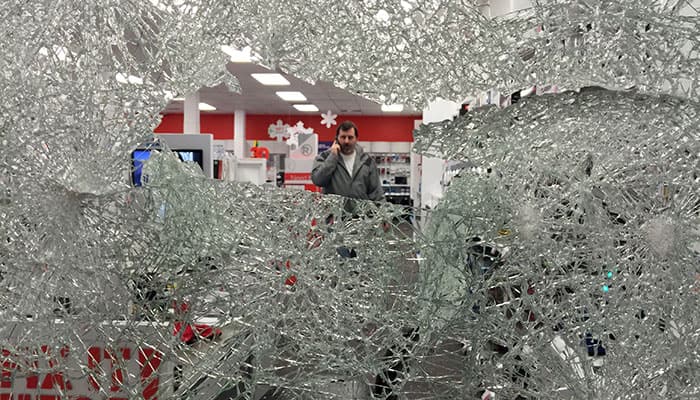 a man talks on the phone at a Radio Shack that was vandalized, in Berkeley, Calif., as protesters angered by police killings in Missouri and New York demonstrated in the streets.