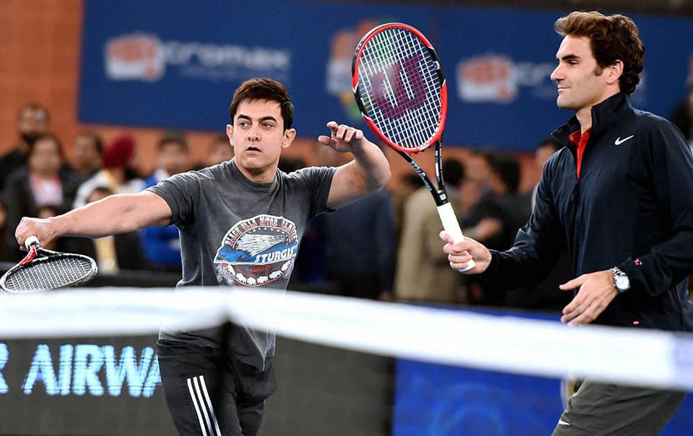 Bollywood actor Aamir Khan plays a shot as tennis star Roger Federer looks on during the IPTL in New Delhi.