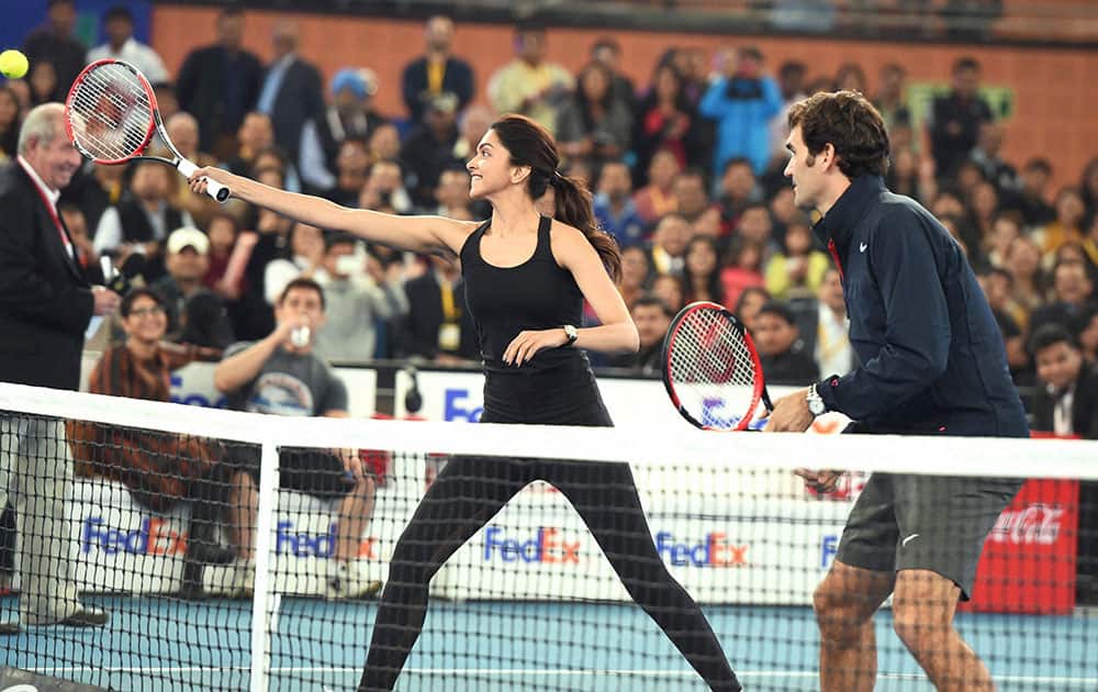 Bollywood actress Deepika Padukone hits the ball as tennis star Roger Federer looks on during an IPTL match in New Delhi.