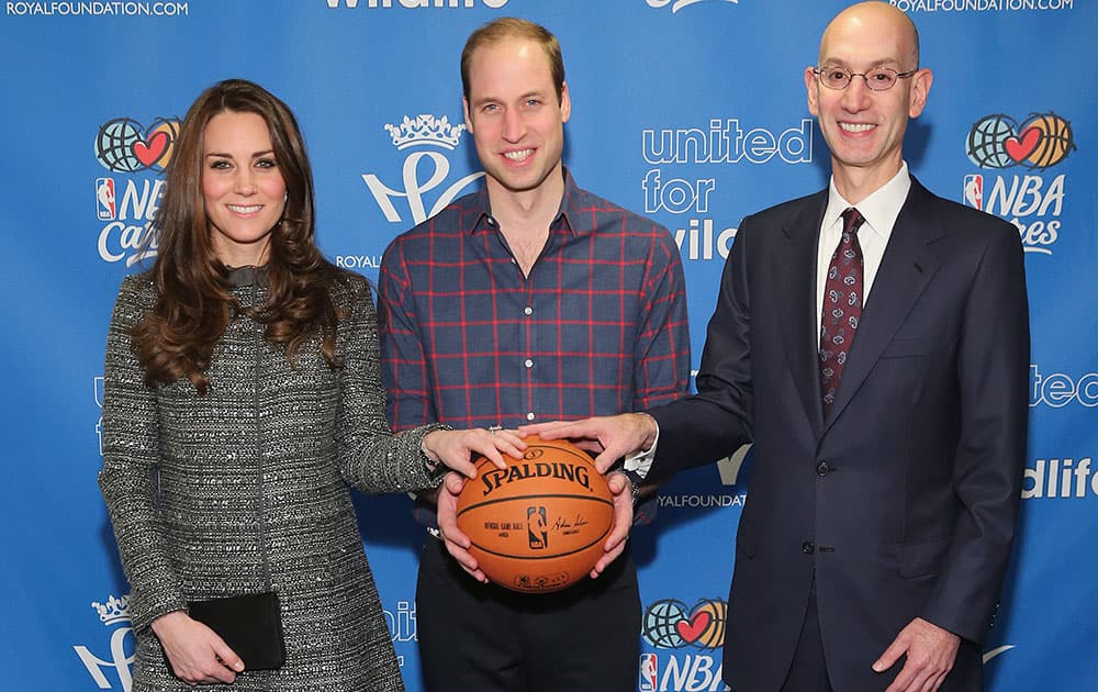 Britain's Prince William, the Duke of Cambridge, center, and Kate, the Duchess of Cambridge, left, pose for a photo with NBA Commissioner Adam Silverwhile attending an NBA basketball game between the Cleveland Cavaliers and Brooklyn Nets, in New York.