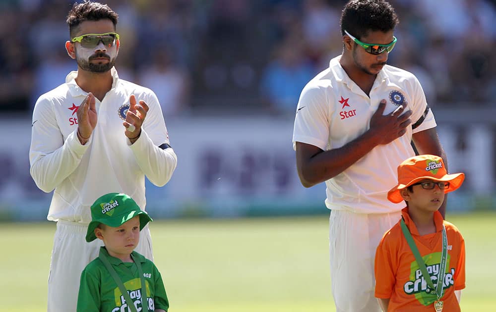 India's cricket players Virat Kohli, back left, and Varun Aaron, back right, wear black armbands as a tribute to Australian cricket player Phillip Hughes during a ceremony at the beginning of a cricket match against Australia in Adelaide, Australia.