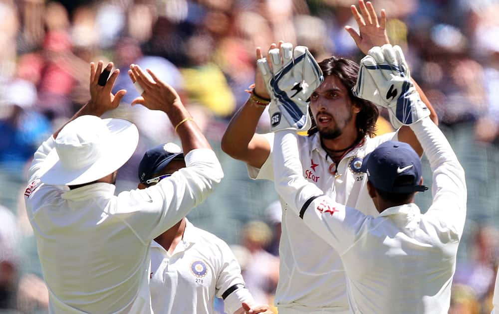 India's Ishant Sharma, second right, celebrates with teammates after taking the wicket of Australia's Chris Rogers for 9 runs during the first day of a cricket match in Adelaide, Australia.