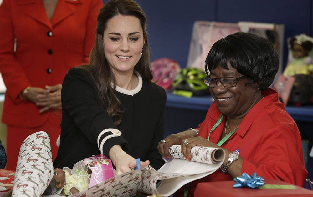 Kate, the Duchess of Cambridge, left, wraps presents for children with volunteer Mary Dawkins at the Northside Center for Childhood Development in New York.