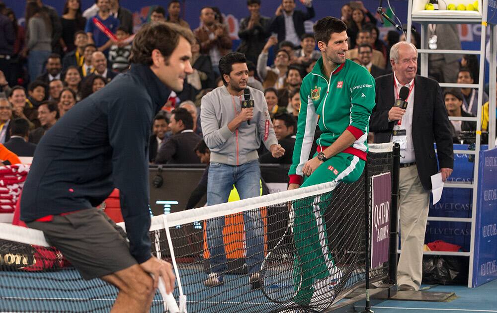 Micromax Indian Aces player Roger Federer and Musafir.com UAE Royals Novak Djokovic sit on the net during a match with Indian Bollywood actors, on the sidelines of the International Premier Tennis League, in New Delhi.