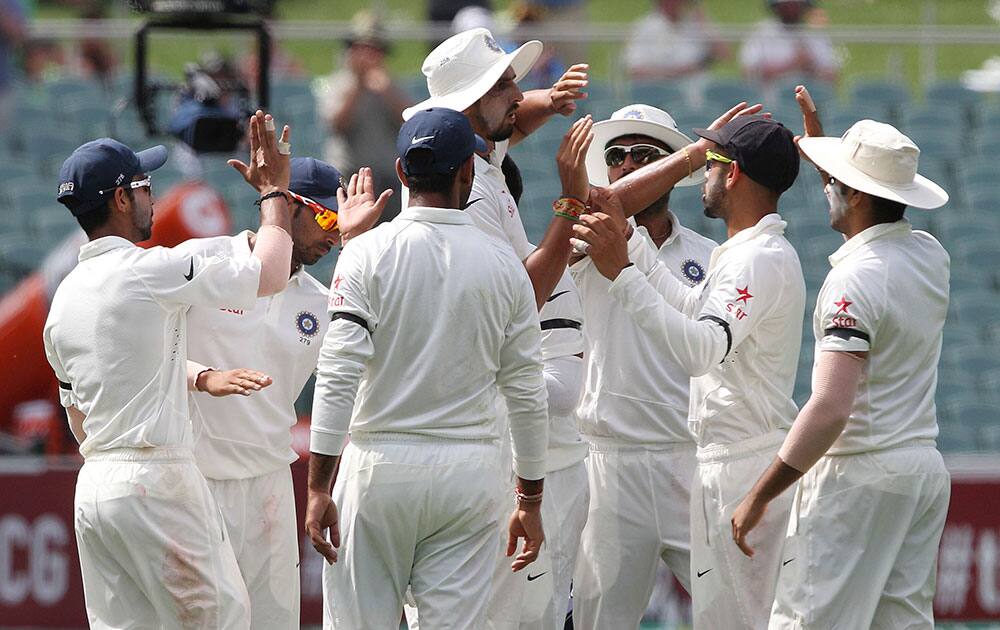 India's Ishant Sharma, center, celebrates catching Australia's David Warner during the first day of a cricket test match in Adelaide, Australia.