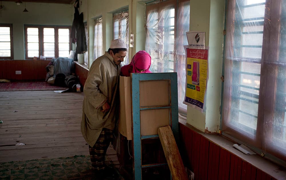 Ghulam Mohammad Dar, a Kashmiri man helps her sick wife Parveena Dar, as they cast their votes during the third phase polling of the Jammu and Kashmir state elections in Charar Sharief, about 40 kilometers (25 miles) south west of Srinagar, Kashmir.