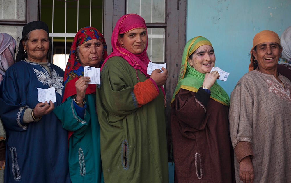 Kashmiri women display their voter slips as they stand in queues to cast their votes during the third phase polling of the Jammu and Kashmir state elections in Chadoora, about 25 kilometers (15 miles) south west of Srinagar, Kashmir.